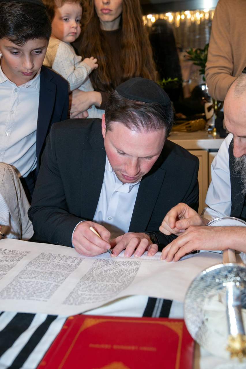 A member of the minyan writing a letter with the sofer’s quill